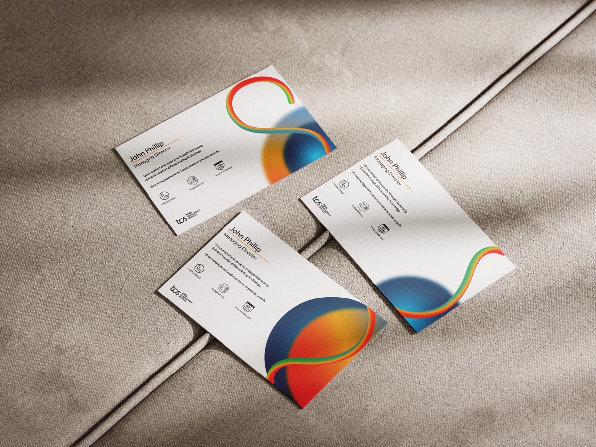 Business cards scattered across soft grey fabric, showing both sides of the design.