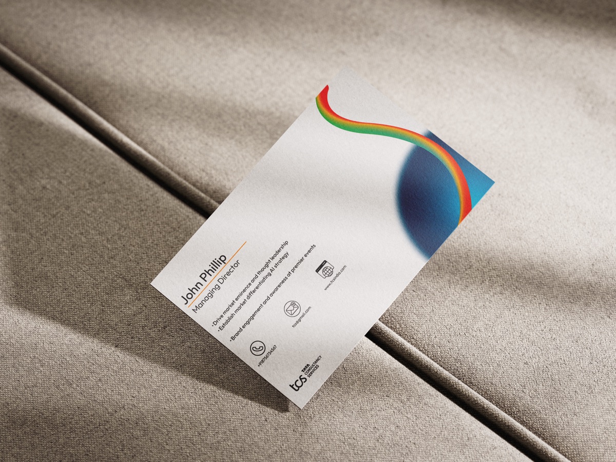 A single business card standing on grey fabric, its circular mark edged in rainbow gradient.